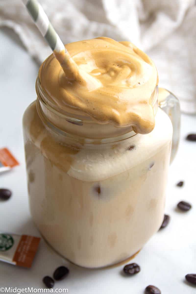 whipped coffee being stirred into a glass of milk