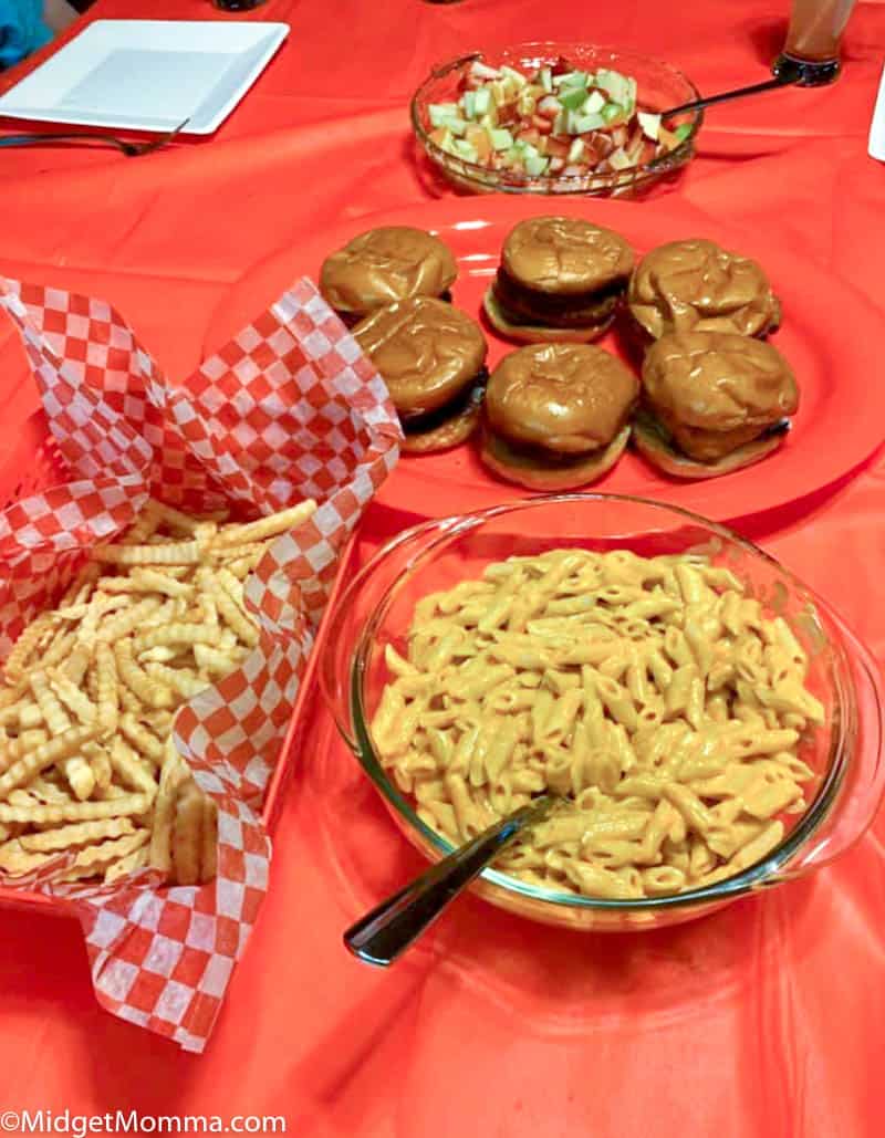 Chic Fil a themed dinner night with mac and cheese, fruit salad in a bowl, copy cat chic-fil-a sandwiches on a platter and fries in a bowl