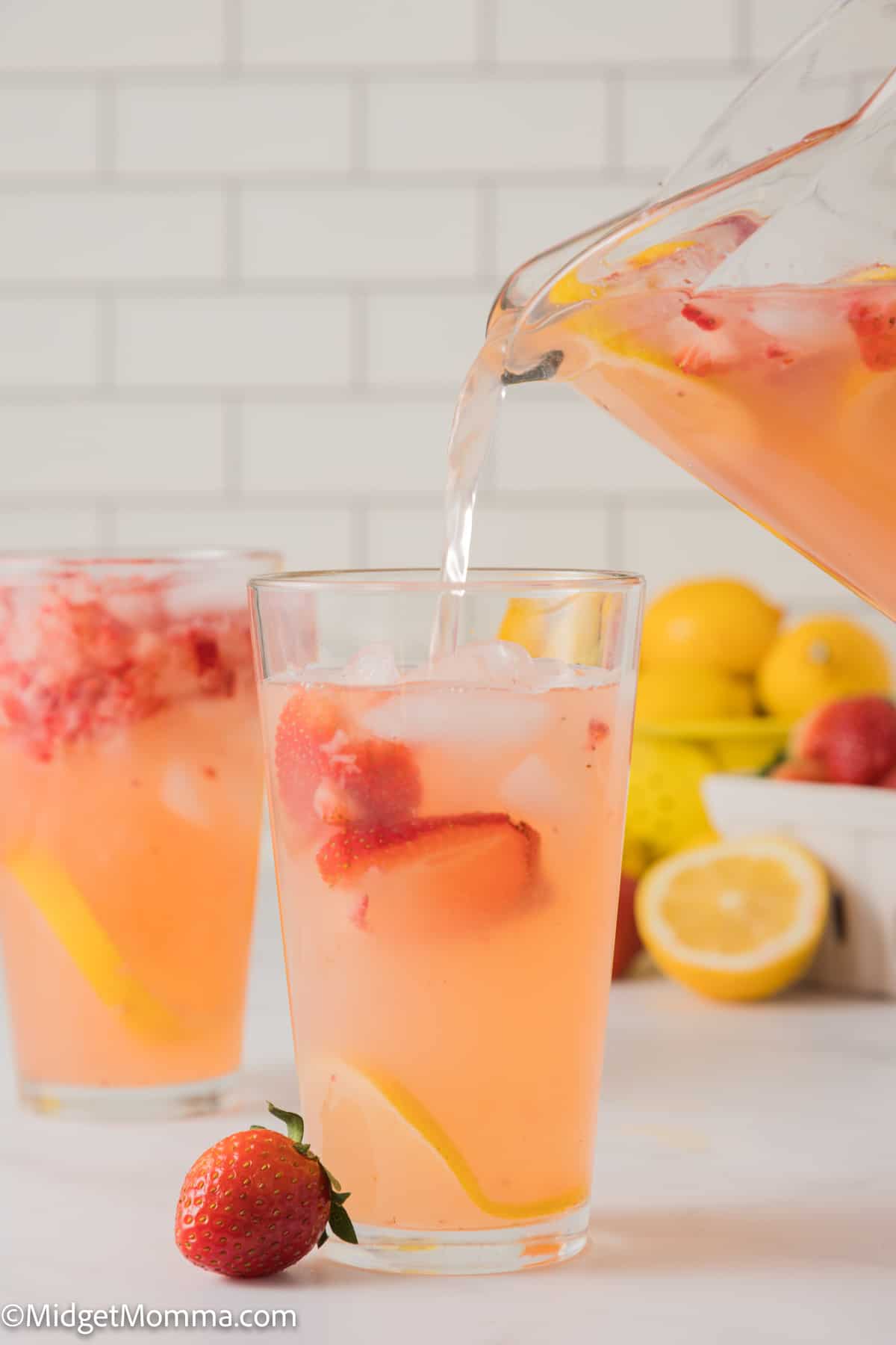 pitcher full of strawberry lemonade being poured into a glass 