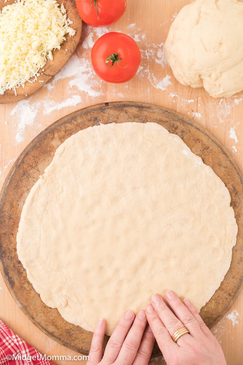 homemade pizza dough being rolled out by hand