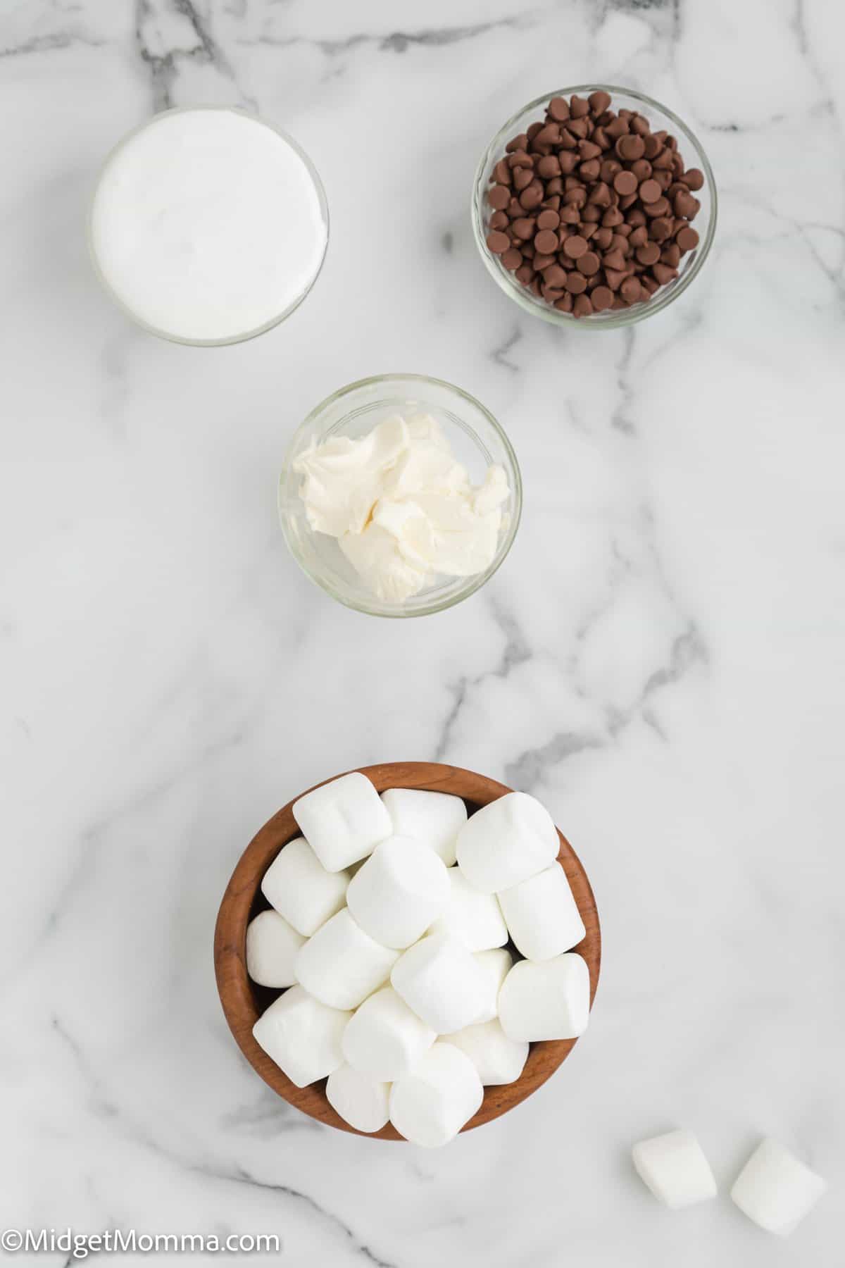 Baked S'mores dip ingredients - marshmallows in a bowl, marshmallow cream in a bowl, cream cheese in a bowl and chocolate chips in a bowl