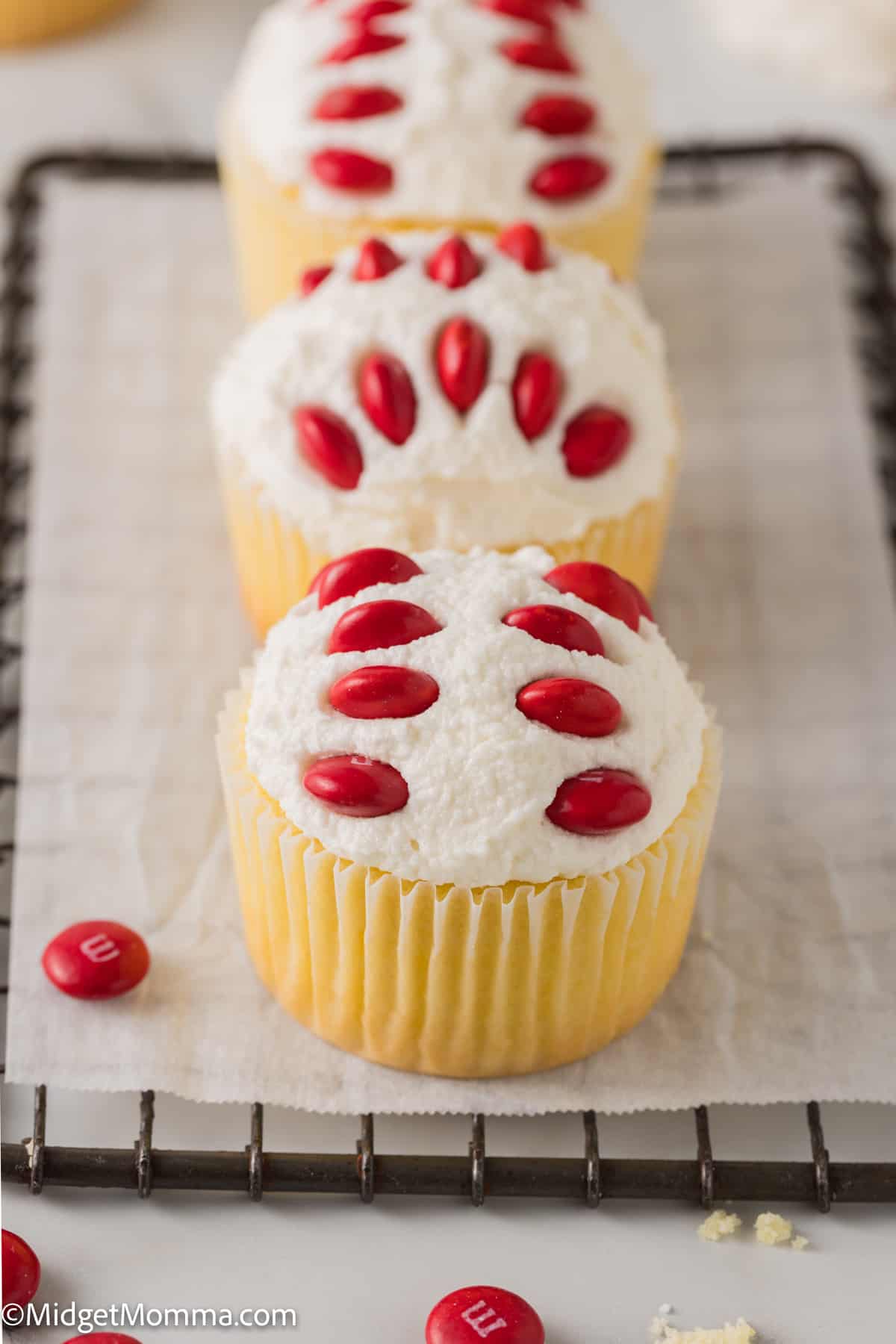 Three baseball cupcakes set out on a baking tray. 