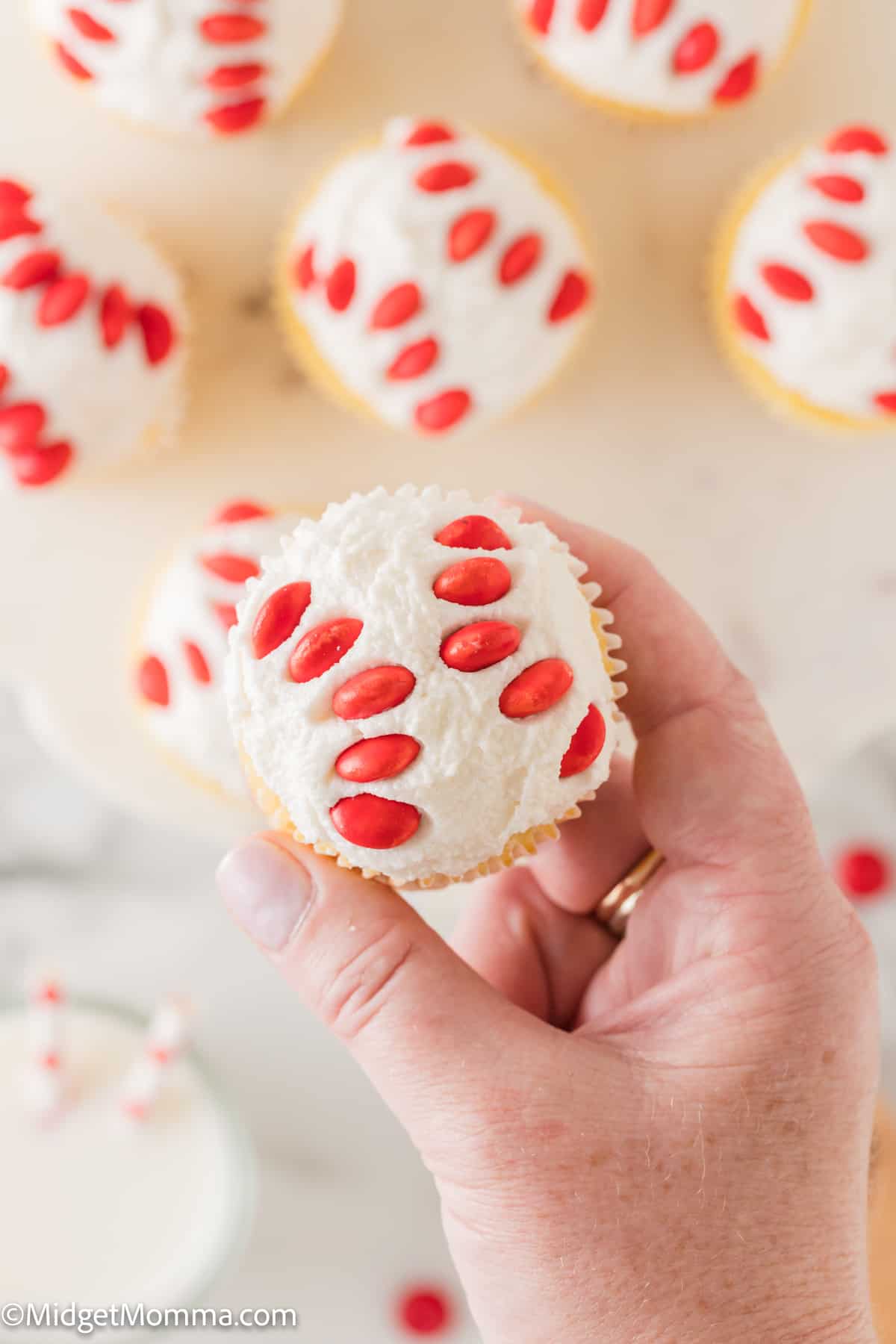 A hand holding a cupcake with red and white M&Ms.