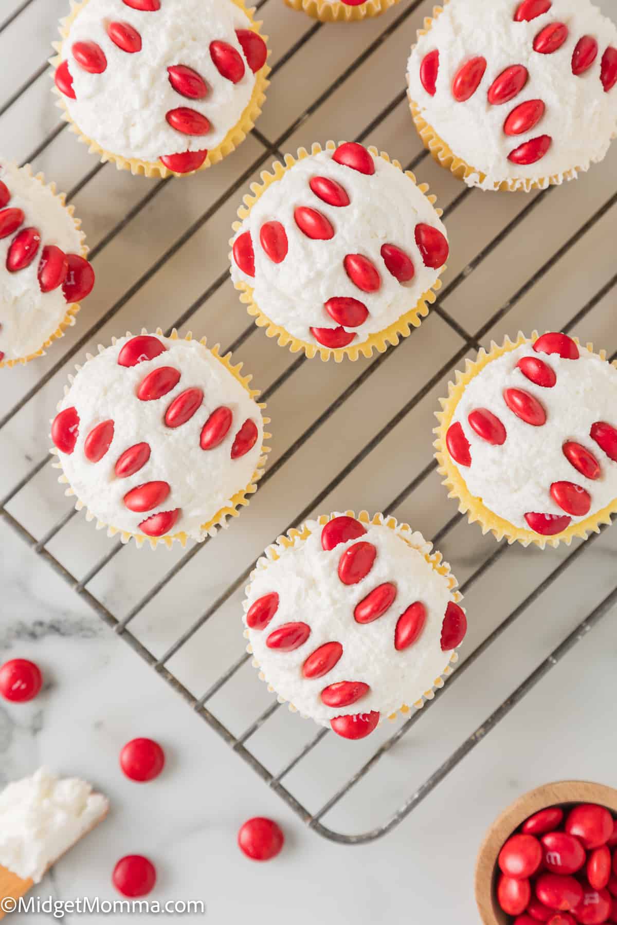 Red and white cupcakes with M&Ms on a rack.