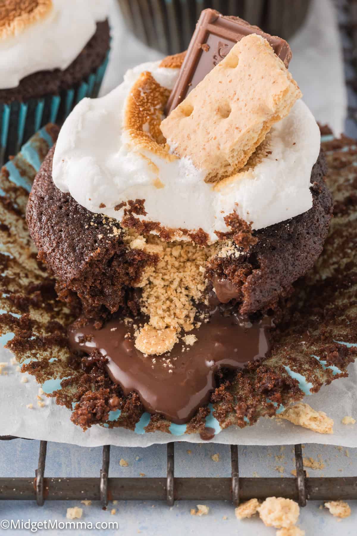 A chocolate cupcake topped with melted marshmallows, a piece of chocolate, and crumbled graham crackers. 