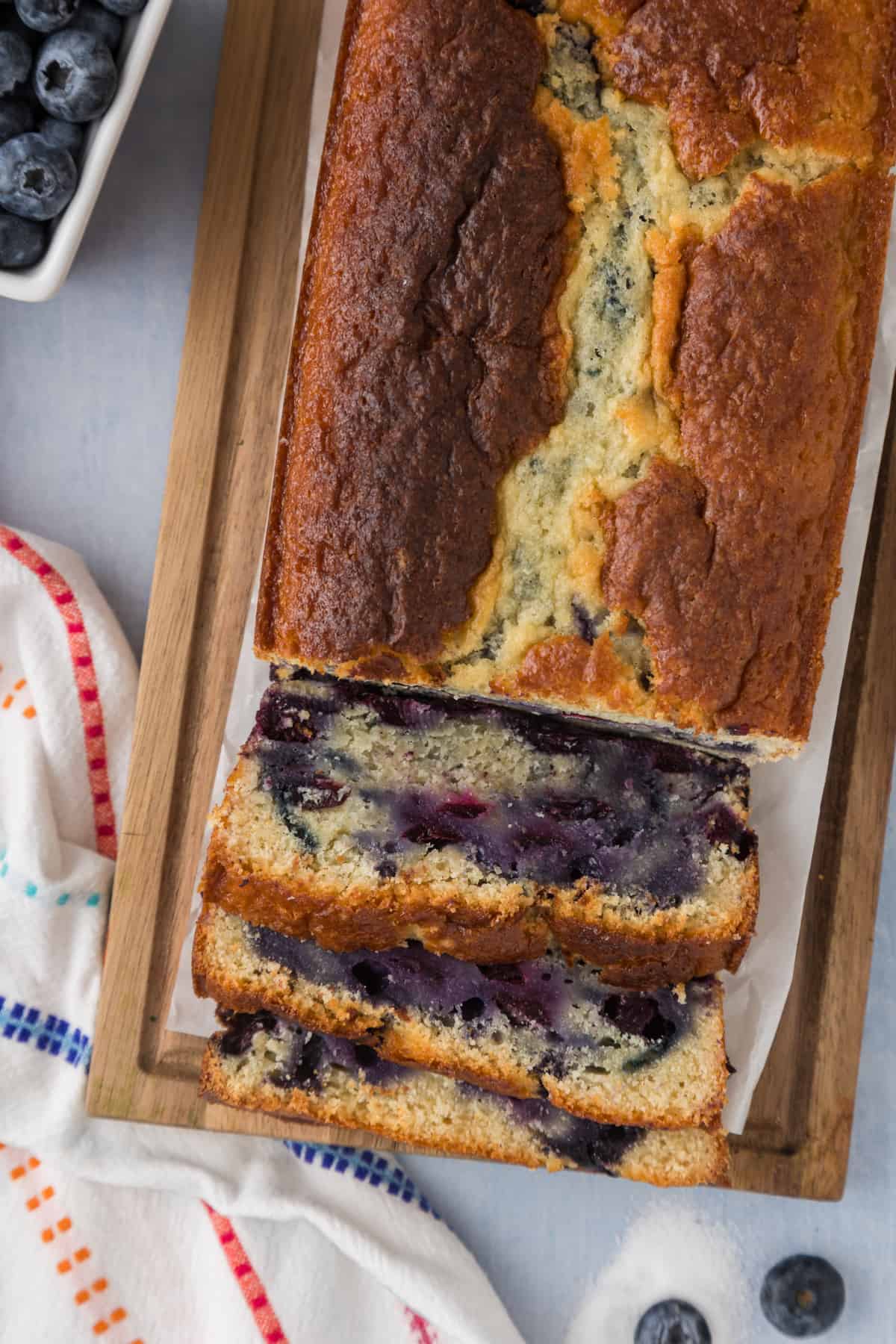 A slice of blueberry bread on a cutting board.
