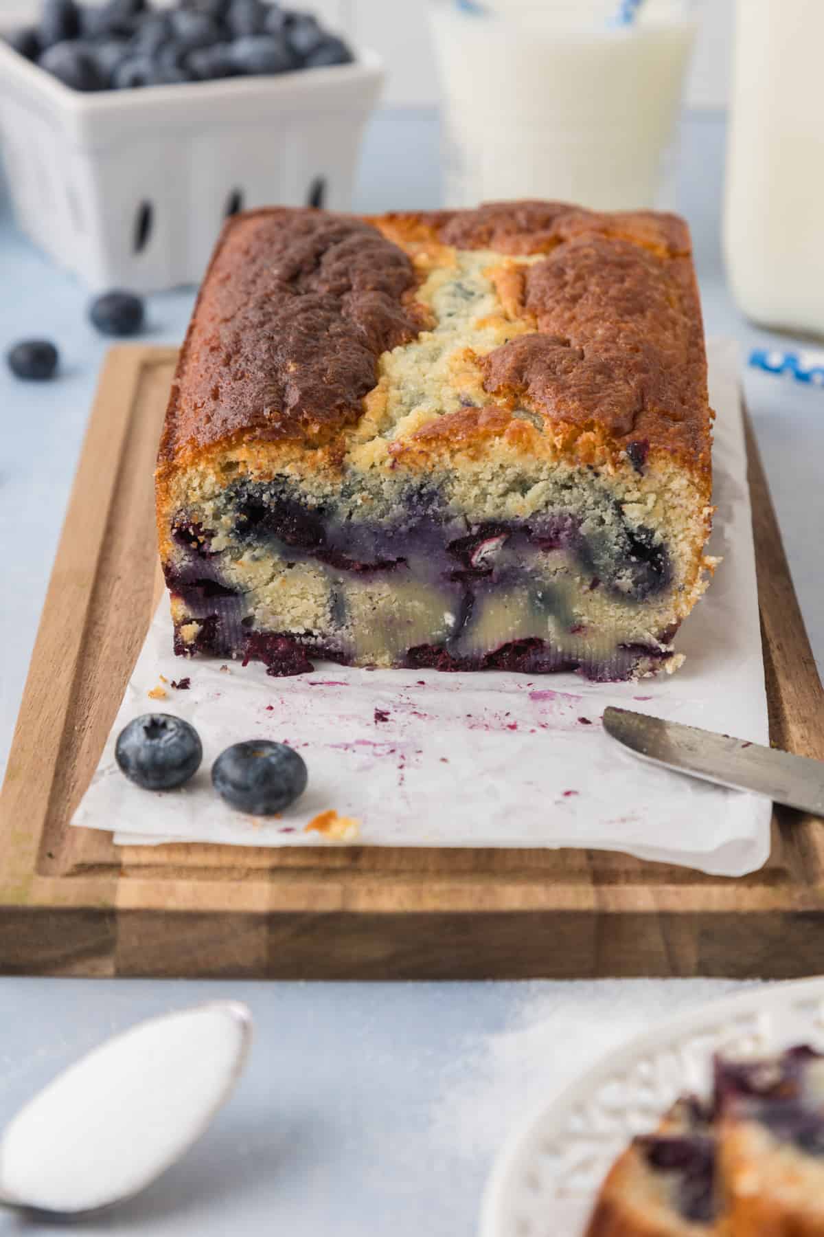 A loaf of blueberry bread on a wooden board.