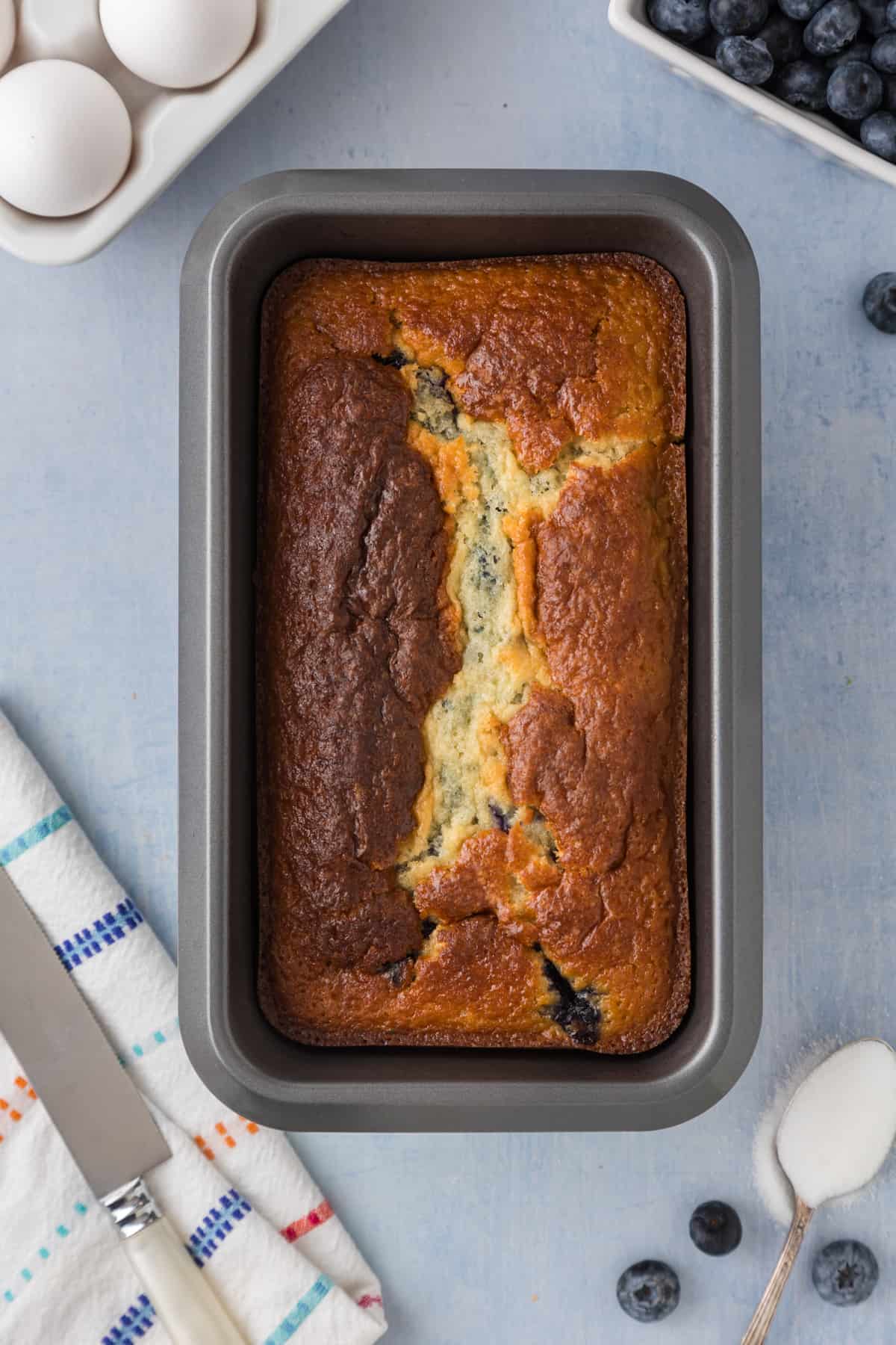 A loaf of Blueberry bread in a bread pan.