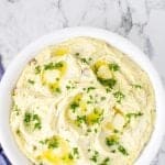 Mashed potatoes in a white bowl with parsley.