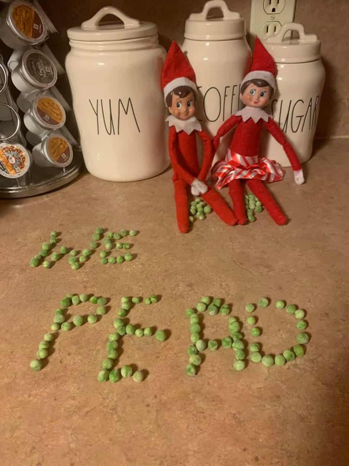 Elf on the shelf with peas on the counter.