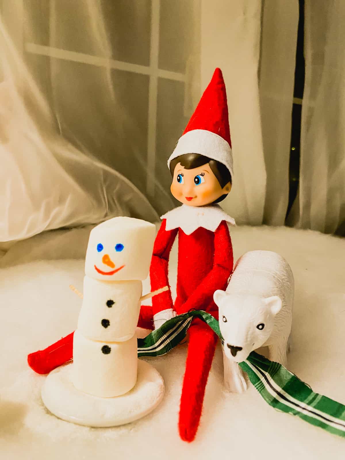 An elf on the shelf with a snowman and polar bear.