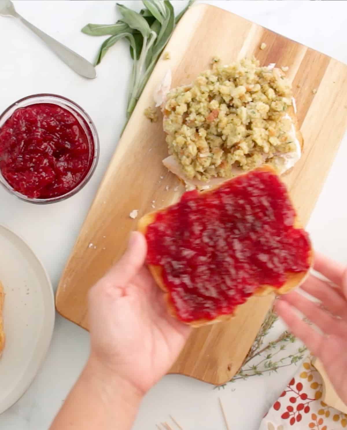 A person is putting cranberry sauce on a slice of bread.
