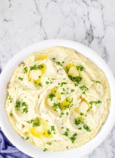 Mashed potatoes in a white bowl with parsley.