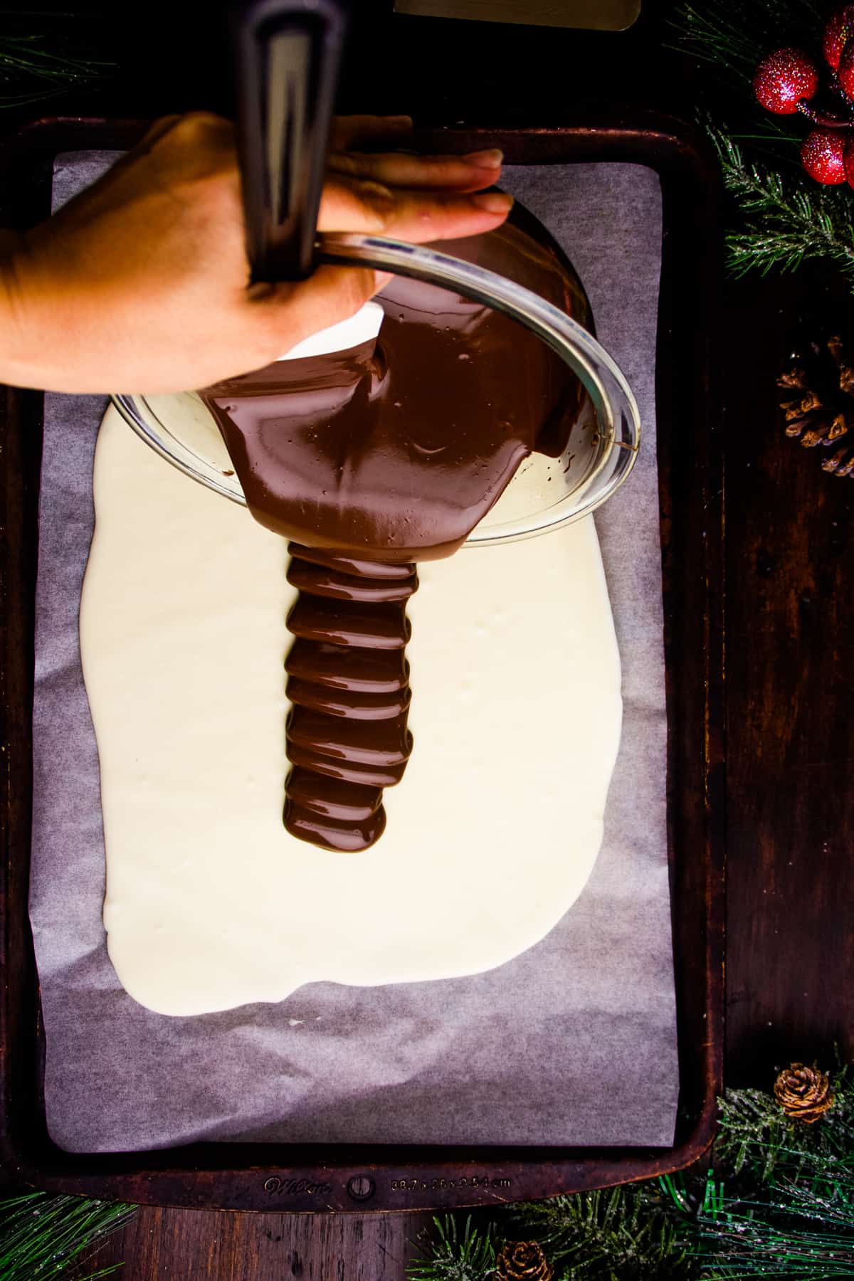 melted chocolate being poured on top of white chocolate to make peppermint bark