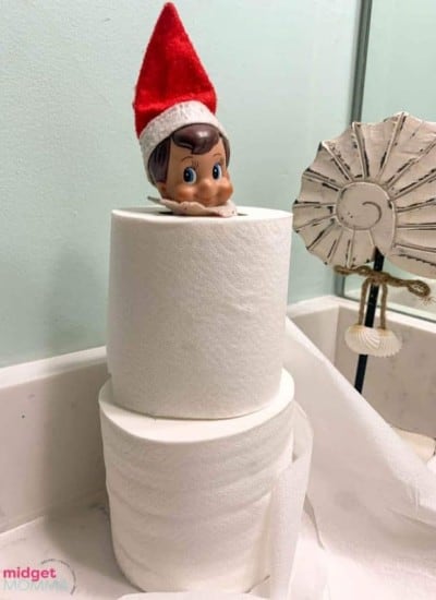 A toilet paper roll with a elf on top.