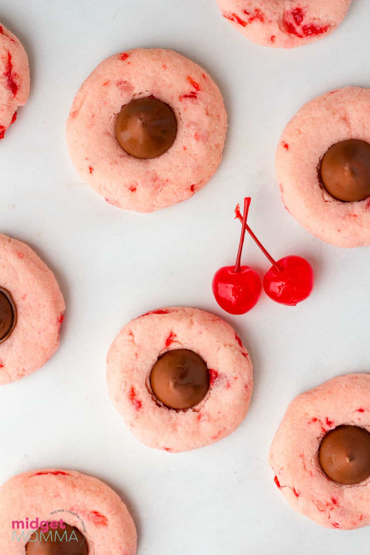 Cherry cookies with chocolate chips and cherries on a white surface.