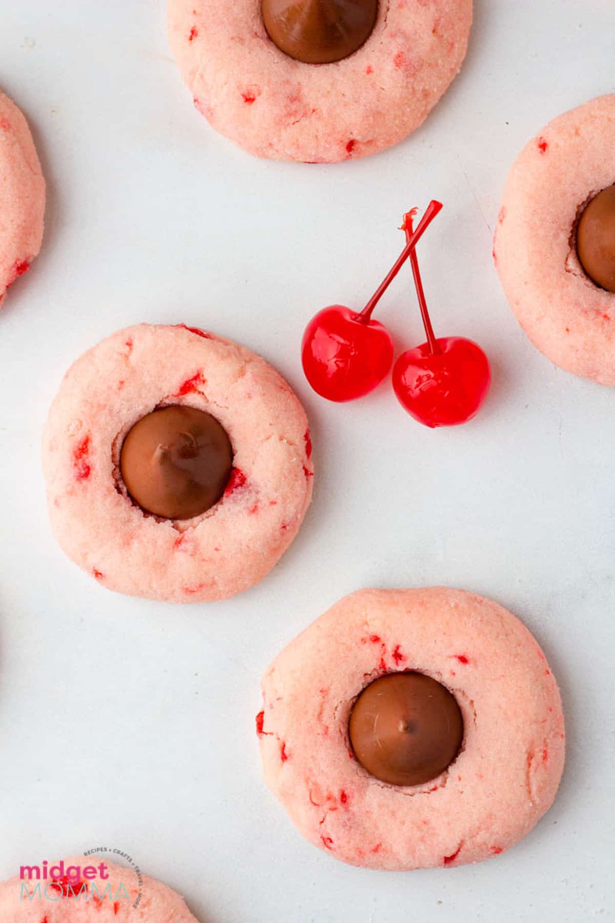 A plate of cherry cookies with chocolate chips on top.