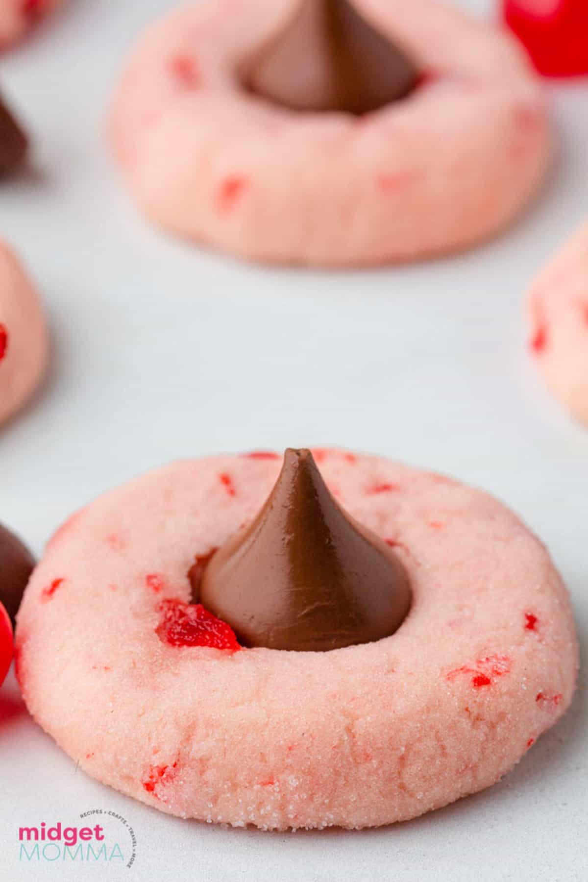 A cherry cookies with a chocolate kiss on top.