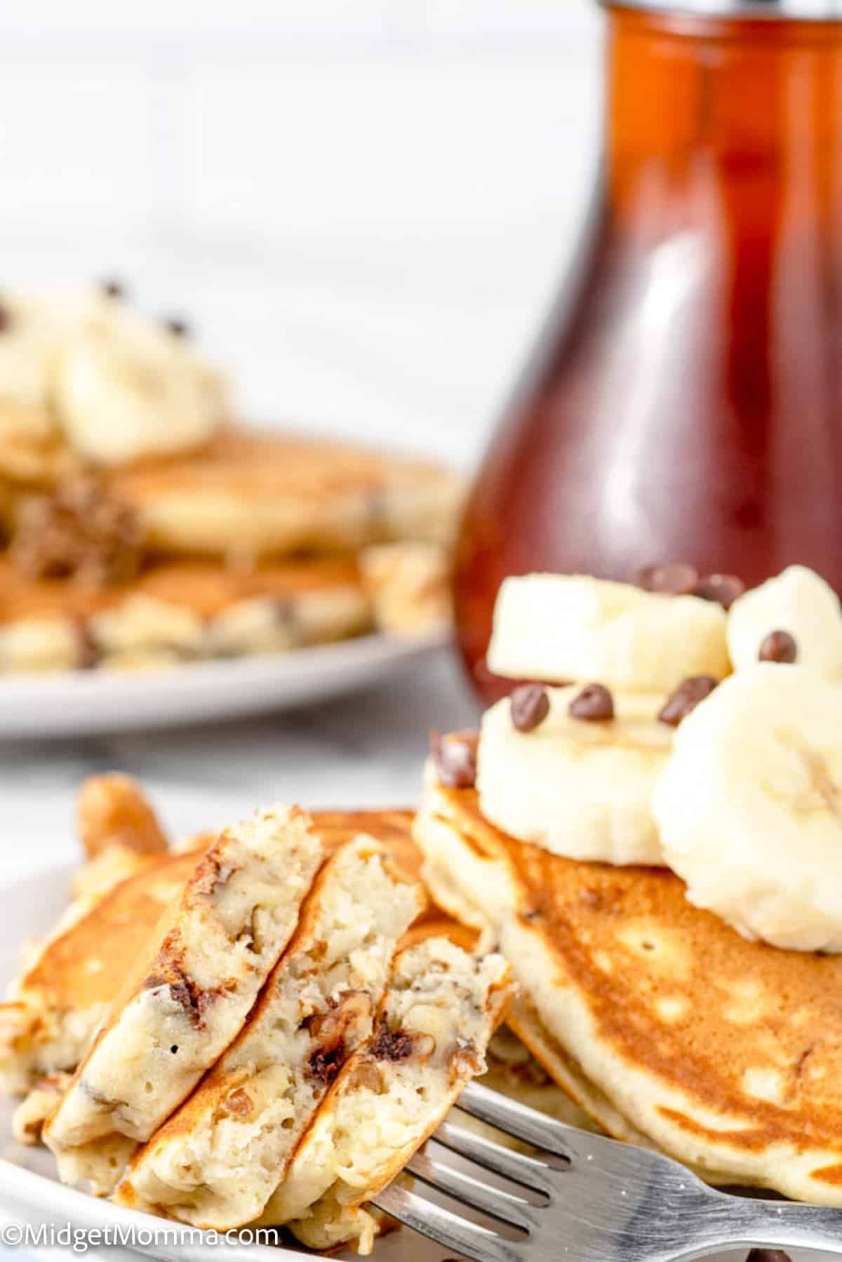 close up photo of a fork full of banana chocolate chip walnut pancakes on a fork