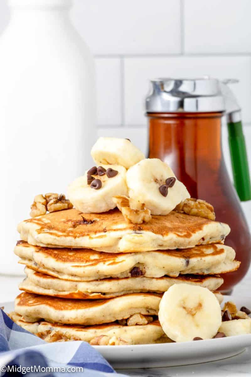 front photo of a stack of Chunky Monkey Pancakes on a plate with a bottle of real maple syrup in the background