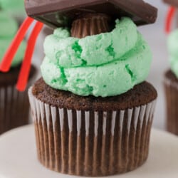 Chocolate cupcakes with green frosting and a graduation hat.