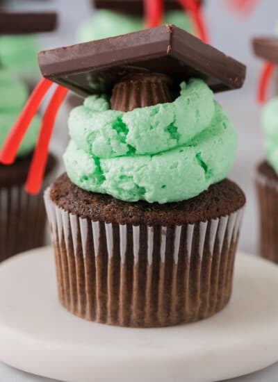 Chocolate cupcakes with green frosting and a graduation hat.