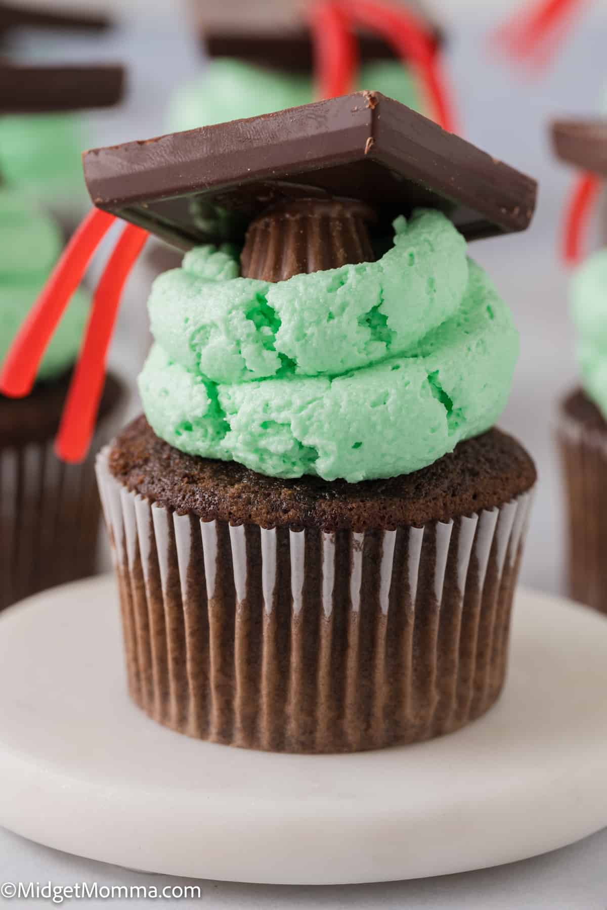 Chocolate cupcakes with green frosting and a graduation hat.