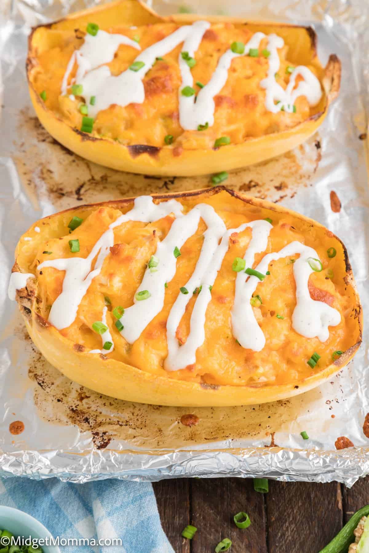 2 spaghetti squash shells stuffed with buffalo chicken spaghetti squash recipe and drizzled with ranch dressing on a baking sheet