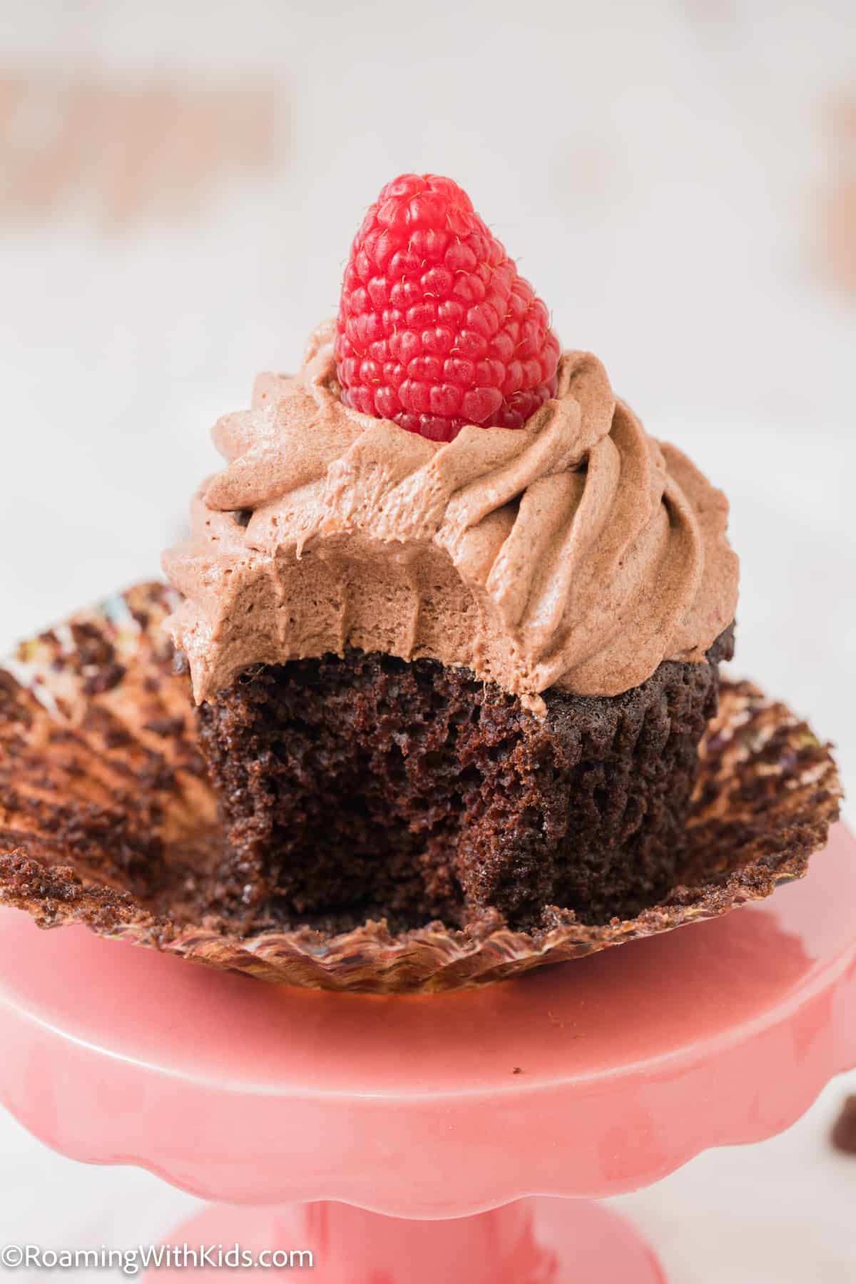 Chocolate Raspberry Cupcake with a bite taken out of it sitting in a cupcake wrapper