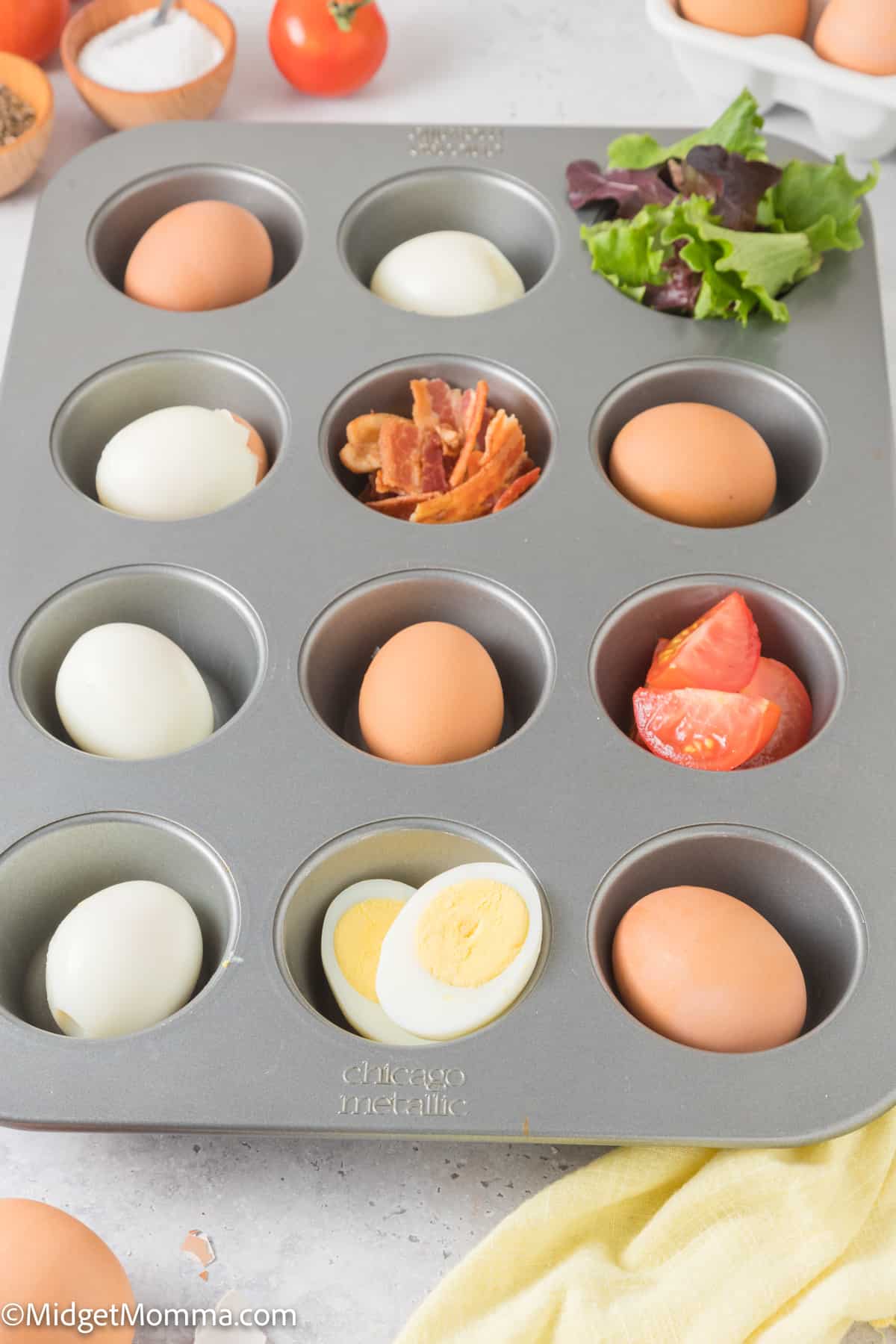 A muffin tin with eggs, bacon, tomatoes and other ingredients.