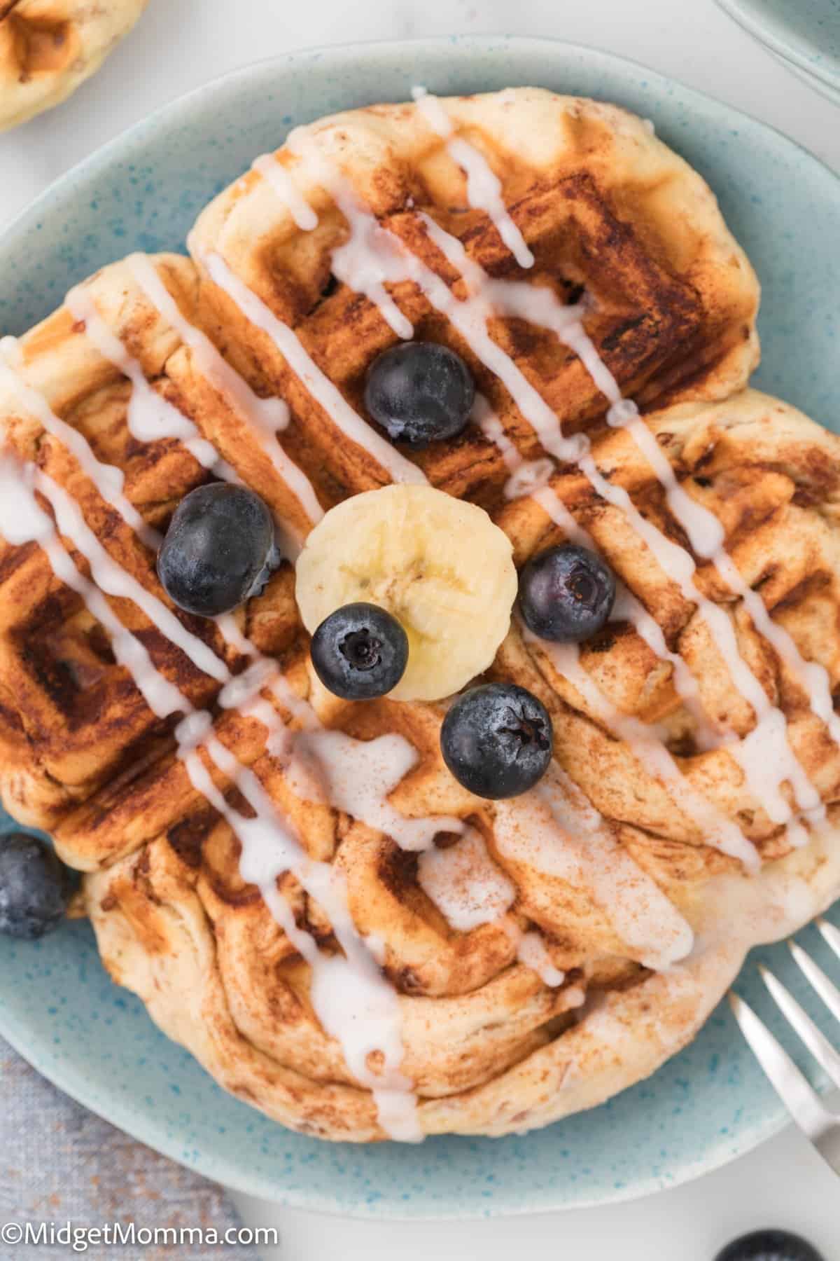overhead photo of Cinnamon roll waffles topped with icing, blueberries and bananas