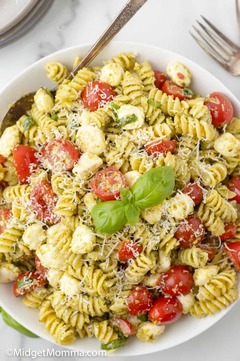 over head photo of pesto pasta salad in a bowl with a serving spoon