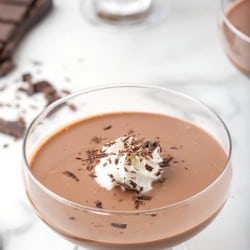 Chocolate pudding in a serving dish with whipped cream and chocolate shreds