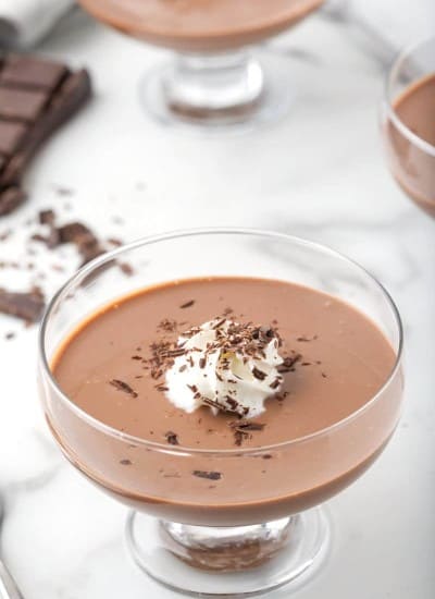 Chocolate pudding in a serving dish with whipped cream and chocolate shreds