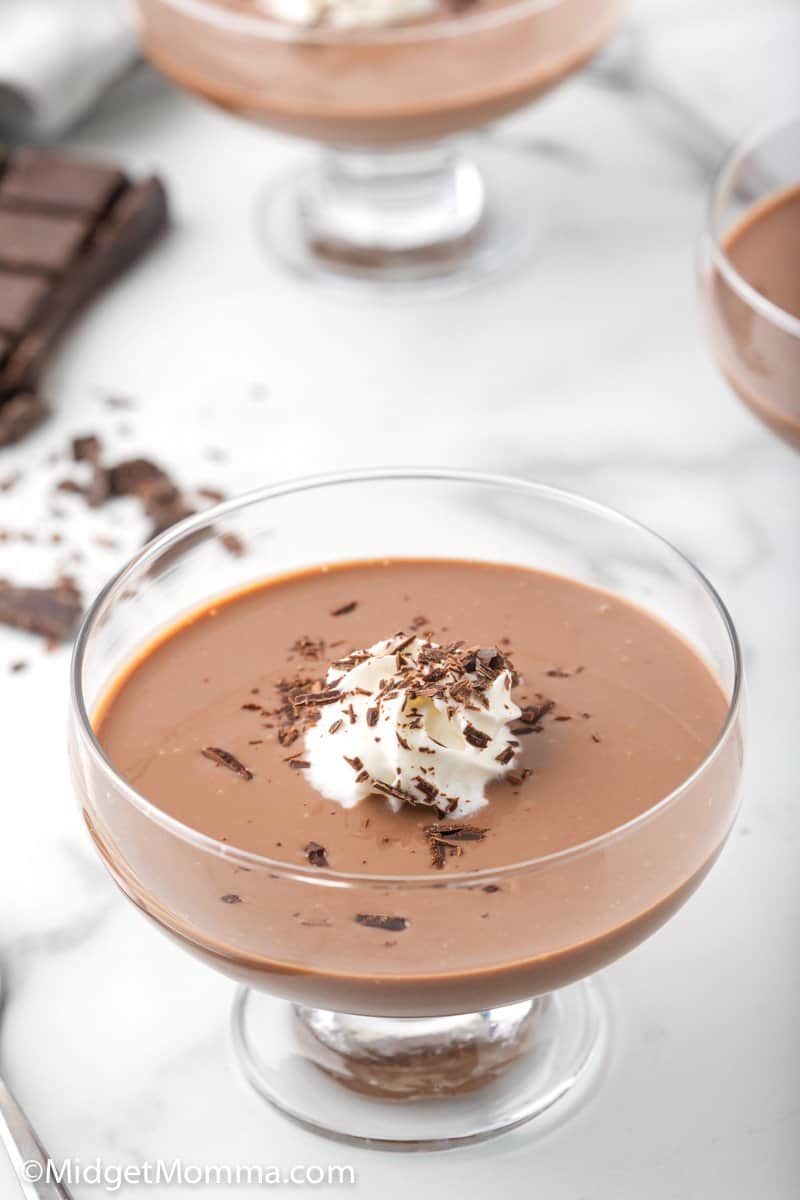 Chocolate pudding in a serving dish with whipped cream and chocolate shreds