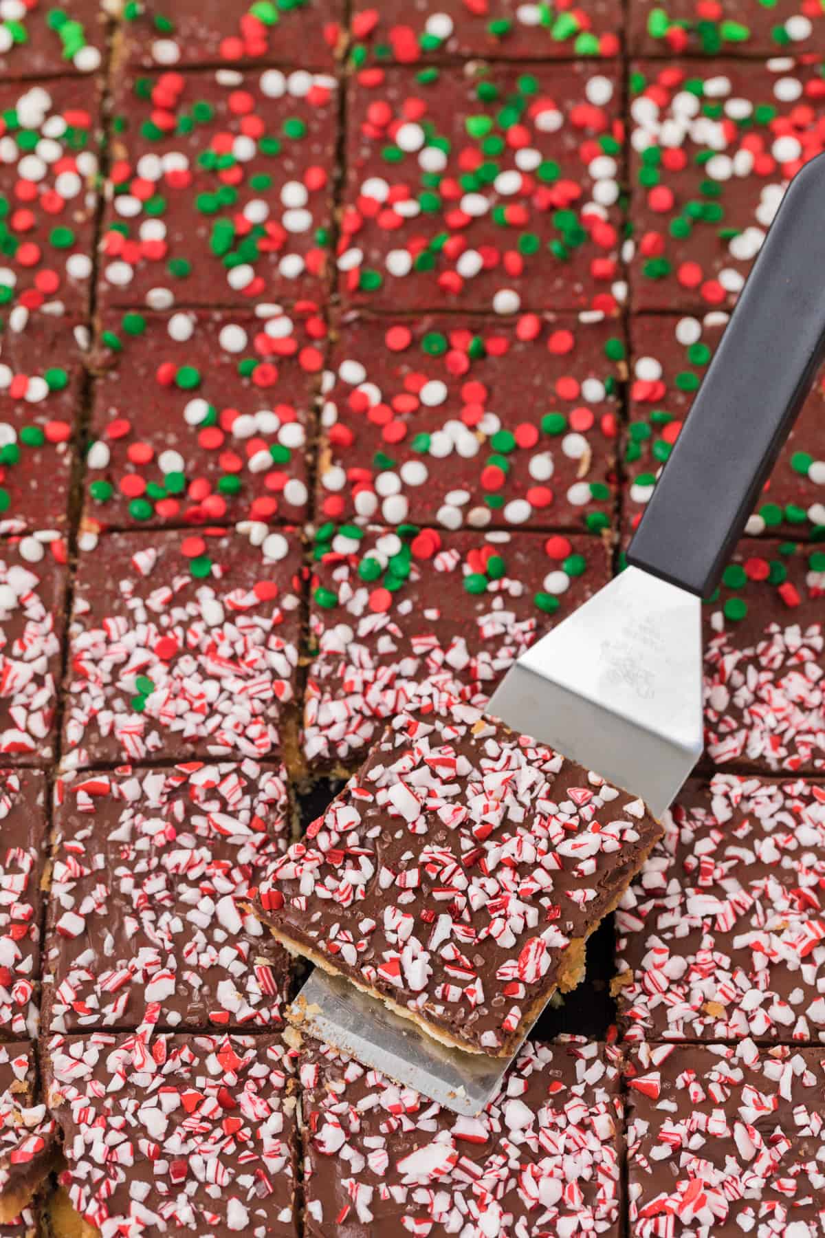 A piece of Christmas Crack with sprinkles on it.
