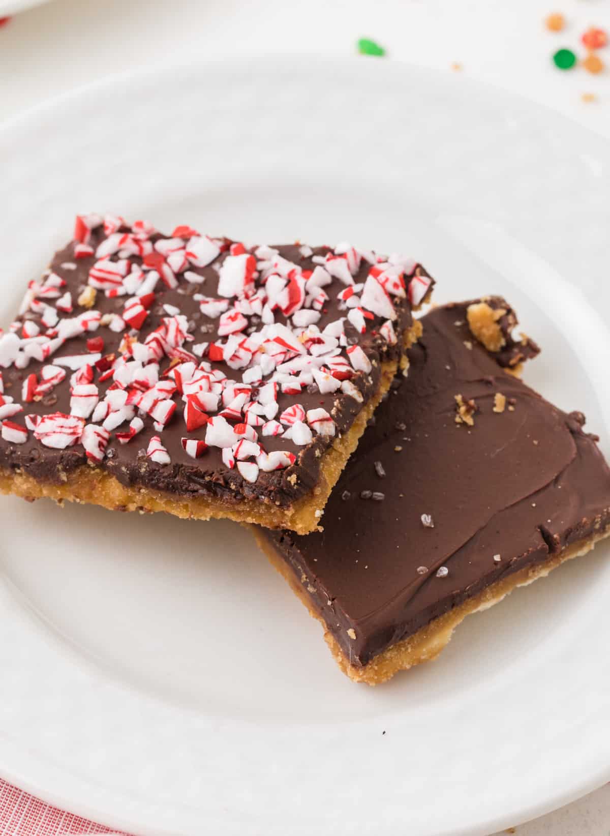 A plate with homemade christmas crack made with saltines with green and red sprinkles on it.