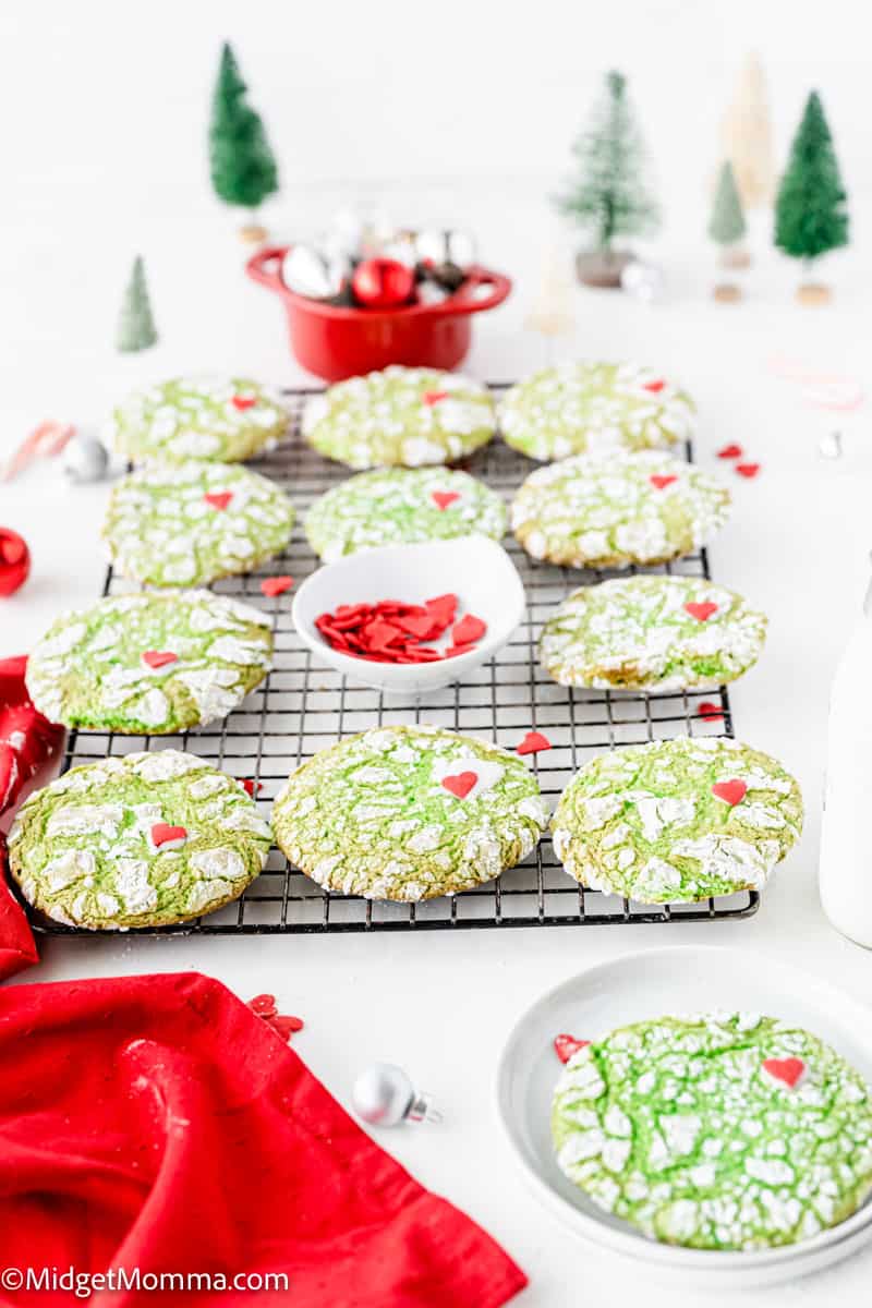 Christmas grinch cookies on a cooling rack with red and green decorations.