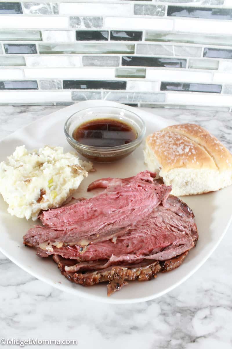 Oven Baked Prime Rib on a plate with au jus, mashed potatoes and a roll