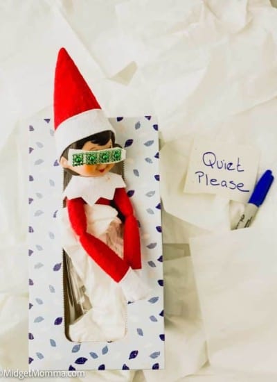 Elf in a box with a sign that says quiet please.