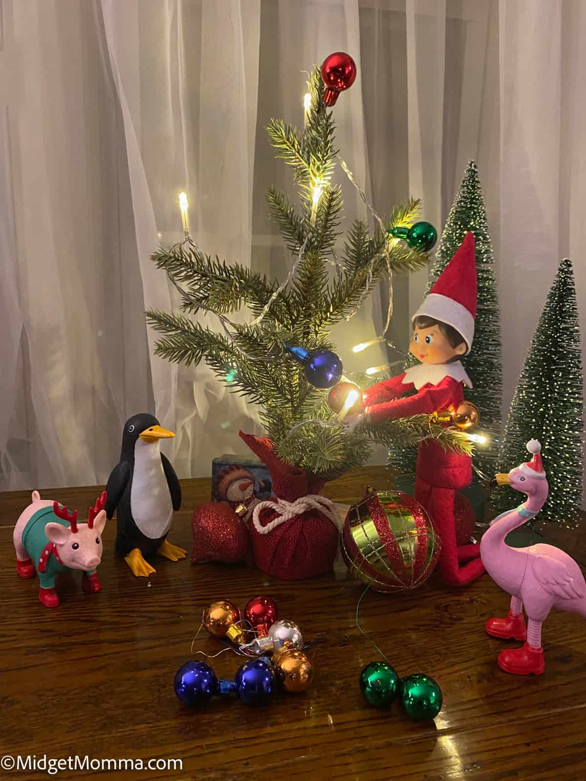 Elf on the shelf with penguins and ornaments.