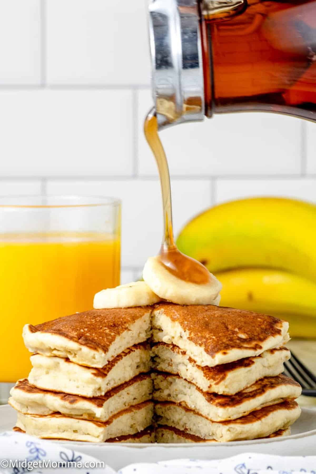 maple syrup being poured on top of banana pancakes