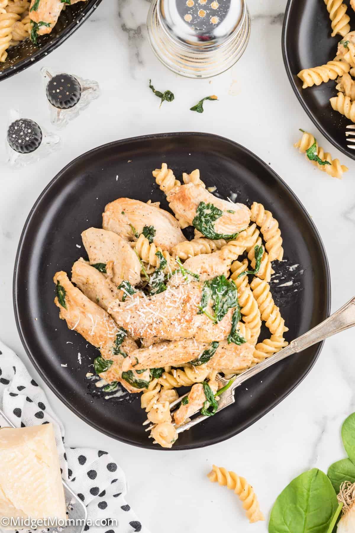 overhead photo of Creamy Garlic chicken pasta with spinach served on a black plate