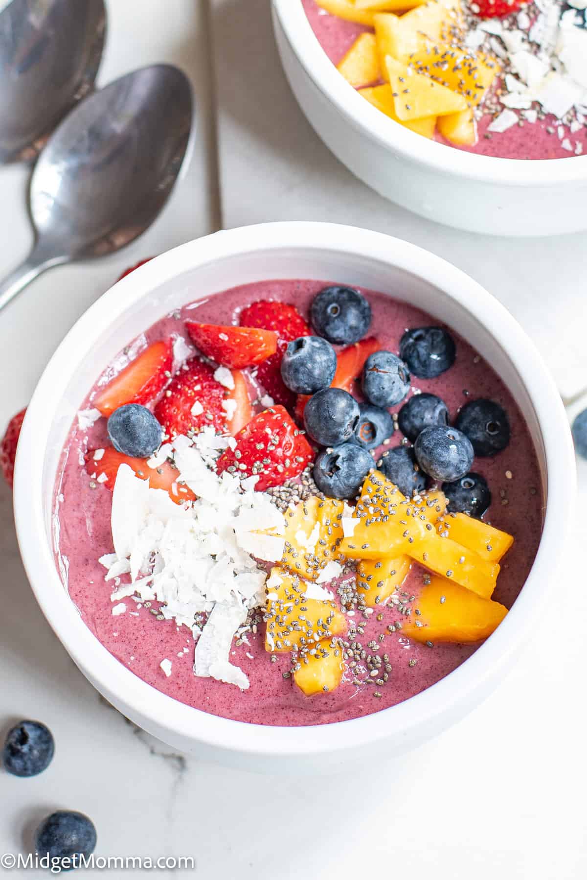Acai Smoothie Bowl topped with mango chunks, strawberries, blueberries, shredded coconut and chai seeds
