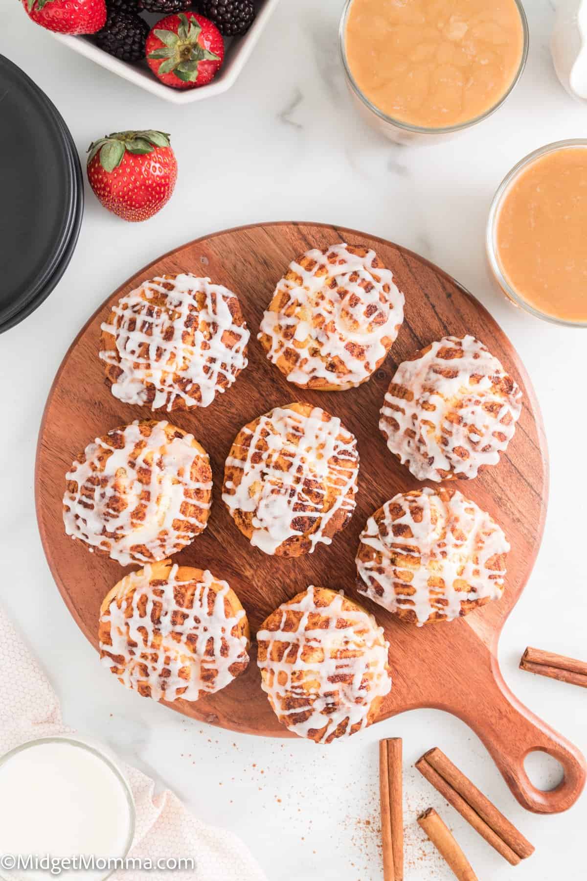 overhead photo of Air Fryer Cinnamon Rolls cooked and frosting on a wooden serving platter