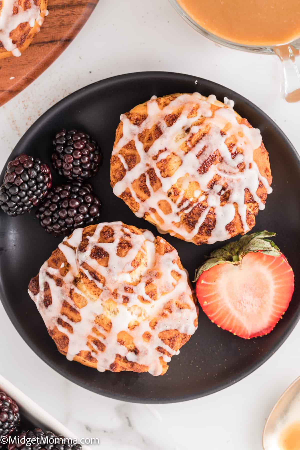 2 cinnamon rolls on a plate with blackberries and strawberries