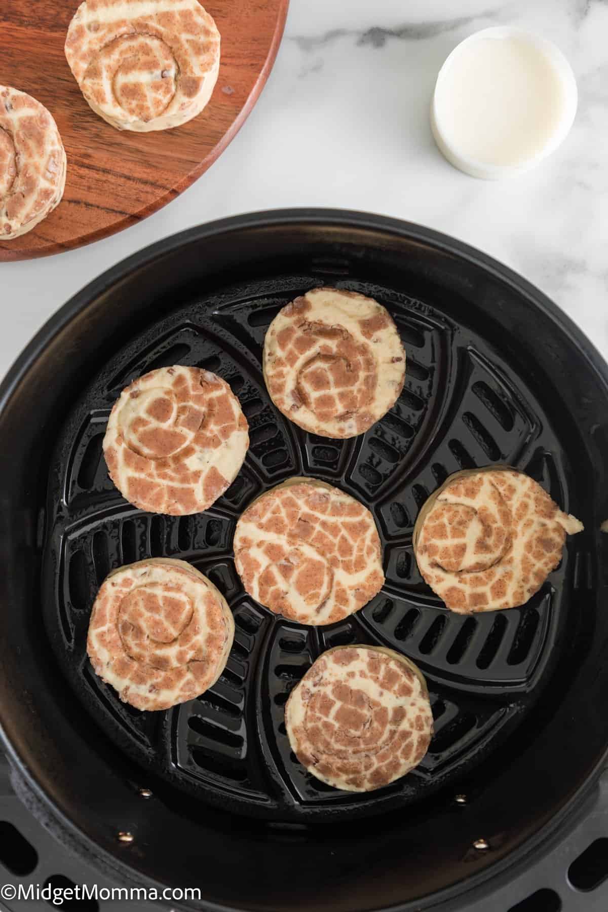 uncooked cinnamon rolls in the basket of an air fryer