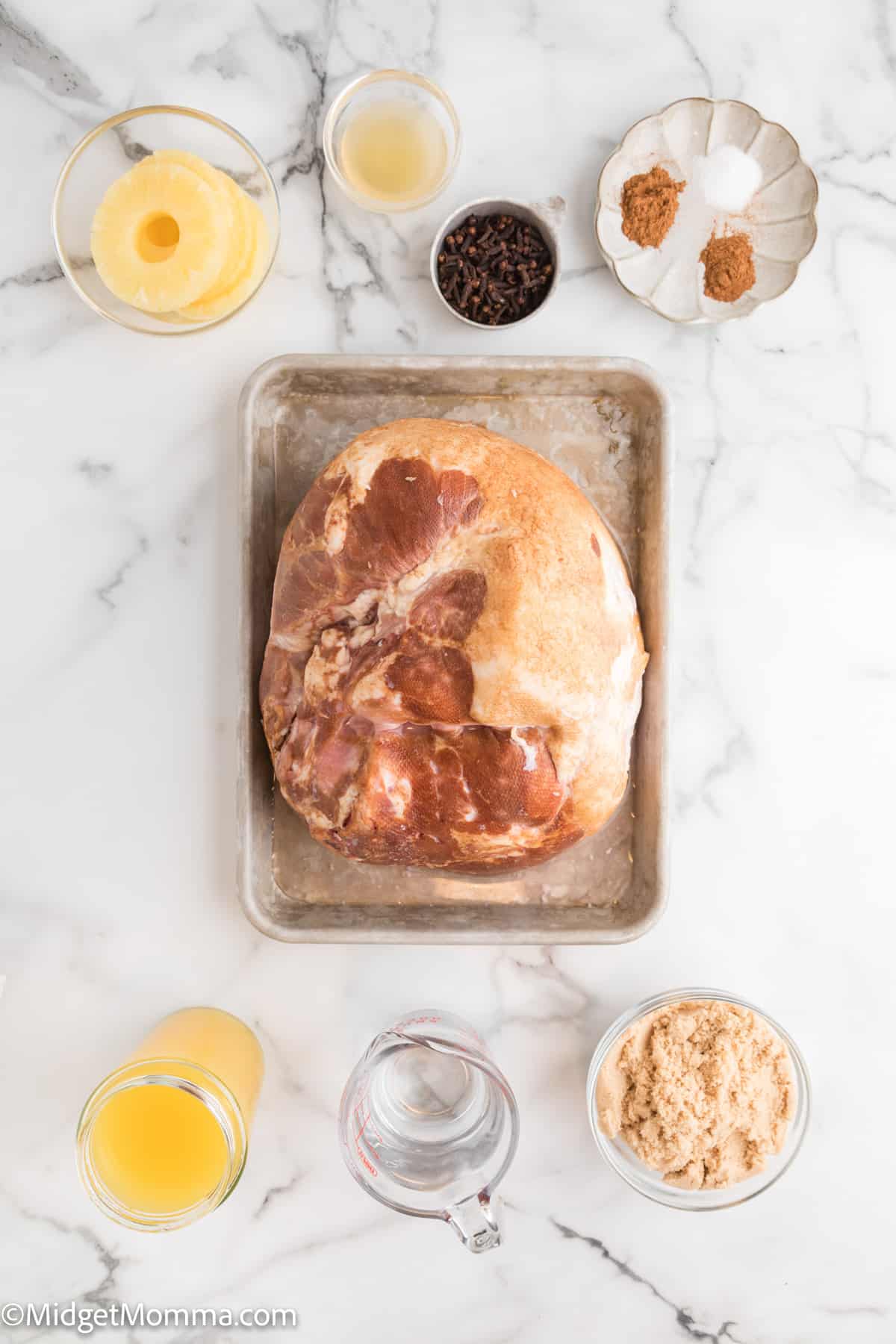 Brown sugar glazed ham with pineapple ingredients - ham, brown sugar and other ingredients in bowls with the precooked ham in a baking dish