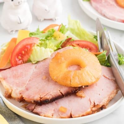 close up photo of baked ham on a plate with a salad