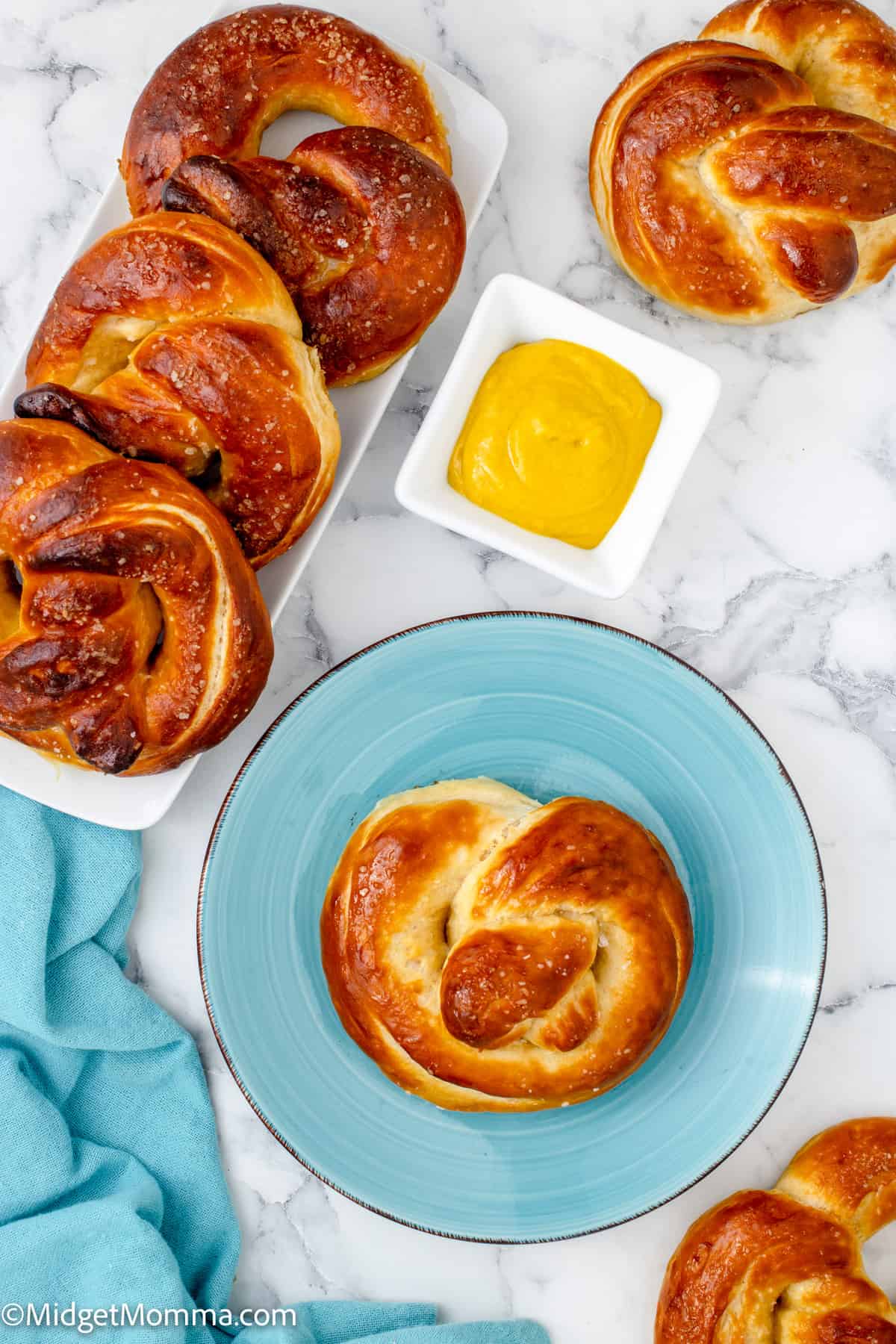overhead photo of a soft pretzel on a plate and other pretzels on a serving tray